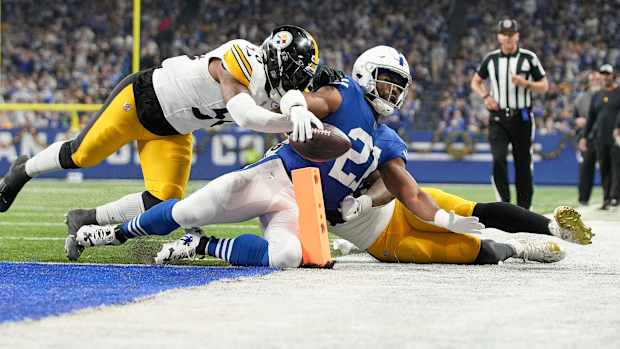 Indianapolis Colts running back Zack Moss (21) slides into the end zone for a touchdown while being chased by Pittsburgh Steelers linebacker Elandon Roberts (50) and Pittsburgh Steelers linebacker Mykal Walker (38) on Saturday, Dec. 16, 2023, during a game against the Pittsburgh Steelers at Lucas Oil Stadium in Indianapolis.  
